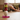Colorful stacked geometric objects on a white Buddha head sculpture with a blurred background of a living room.